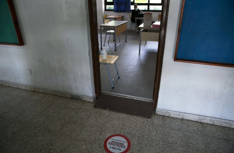  A social distance sign is seen at the entrance of a classroom in a school following the easing of lockdown measures against the spread of the coronavirus disease (COVID-19) on the education sector, in Nicosia, Cyprus, May 13, 2020. (photo credit: REUTERS/YIANNIS KOURTOGLOU)