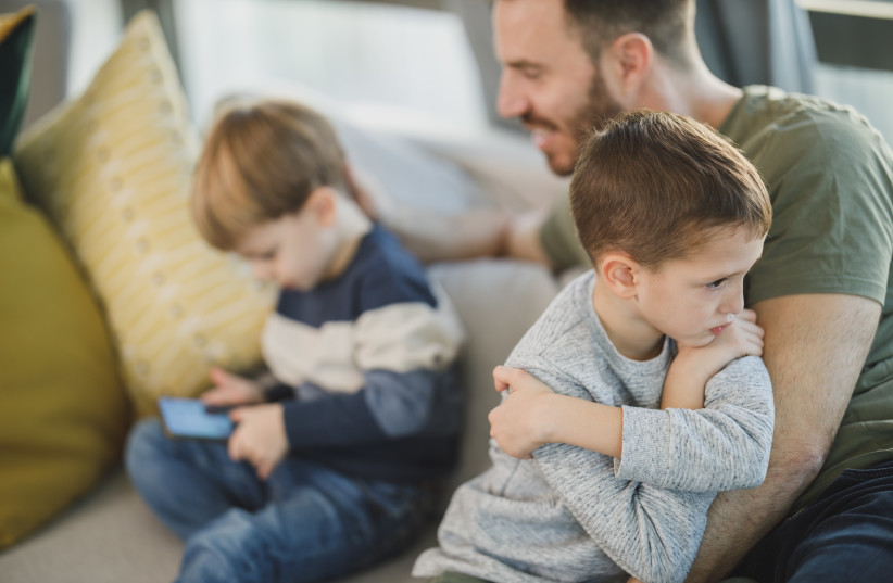  A child and his brother are with their parent, one playing a video game on a phone and the other having a temper tantrum (Illustrative) (photo credit: Direct Media/Stocksnap)