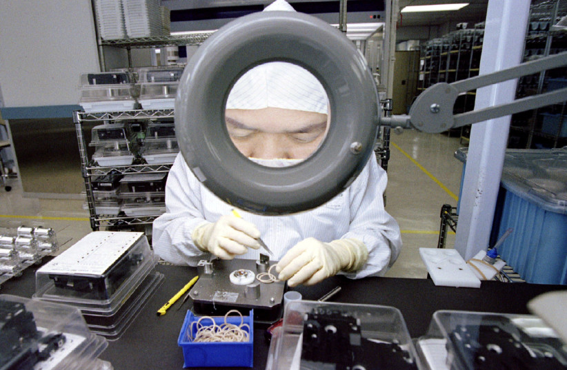  An employee of Seagate Technology is enlarged by a magnifying glass as she concentrates on assembling hard disk drives in a ''clean room'' at one of their Singapore plants May 5.  (credit: REUTERS)