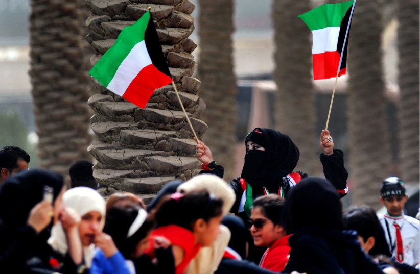  A woman waves two Kuwaiti flags during a military demonstration held at the Marina Mall in Kuwait City, Feb. 28, 2011 (photo credit: Petty Officer 1st Class Joshua L. Kelsey/US Navy/Wikimedia Commmons)