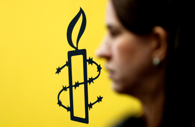  The logo of Amnesty International is seen next to director of Mujeres En Linea Luisa Kislinger, during a news conference to announce the results of an investigation into humans rights abuses committed in Venezuela during protests against President Nicolas Maduro in Caracas, Venezuela February 20, 2 (photo credit: REUTERS/CARLOS JASSO)