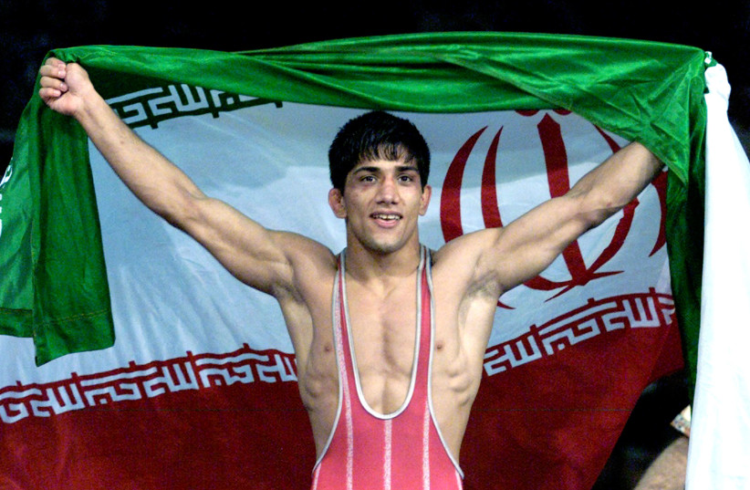  Alireza Dabir of Iran waves his country's flag after winning the gold medal match in the 58kg category of the freestyle wrestling events at the Sydney Olympics October 1, 2000. (photo credit: REUTERS)