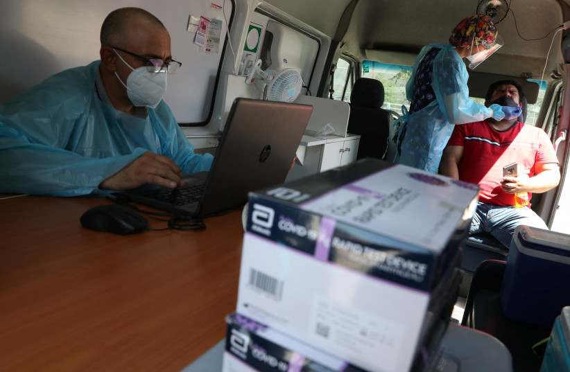  A healthcare worker prepares to test a man for the coronavirus disease (COVID-19) at a mobile testing truck, in Santiago, Chile, January 31, 2022.  (credit: IVAN ALVARADO/REUTERS)