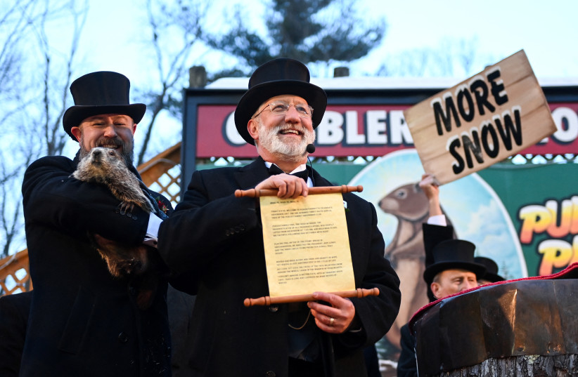  Groundhog Club Inner Circle Vice President Tom Dunkel holds the scroll with Phil's forecast of six more weeks of winter during the 136th Groundhog Day, at Gobblers Knob in Punxsutawney, Pennsylvania, US, February 2, 2022. (credit: ALAN FREED/REUTERS)