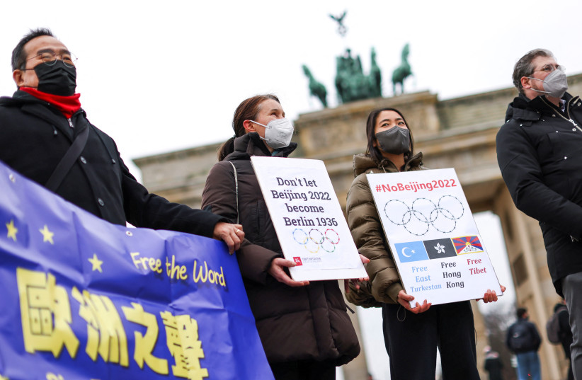 Demonstrators hold signs and banners during a protest against the 2022 Beijing Winter Olympics in front of the Brandenburg Gate, in Berlin, Germany, February 4, 2022. (photo credit: REUTERS/CHRISTIAN MANG)