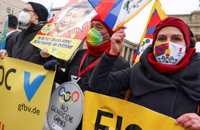 Demonstrators hold signs and Tibetan flags during a protest against the 2022 Beijing Winter Olympics in front of the Brandenburg Gate, in Berlin, Germany, February 4, 2022. (photo credit: REUTERS/CHRISTIAN MANG)