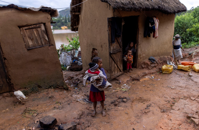 A girl holds a baby outside a damaged house in a flooded area, as Cyclone Batsirai sweeps inland, in Fianarantsoa, Madagascar, February 6, 2022. (photo credit: REUTERS/ALKIS KONSTANTINIDIS)