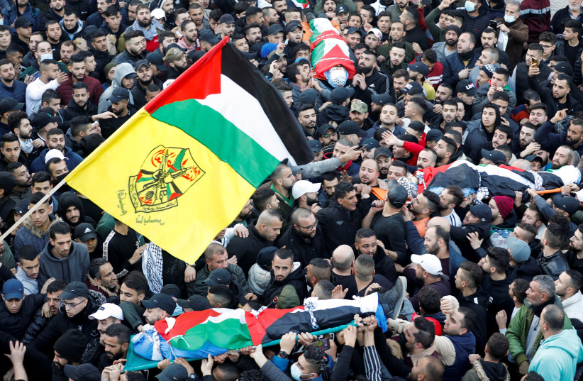 Mourners carry the bodies of three Palestinian gunmen, killed by Israeli forces, during the funeral, in Nablus, in the West Bank, February 8, 2022 (photo credit: RANEEN SAWAFTA/ REUTERS)