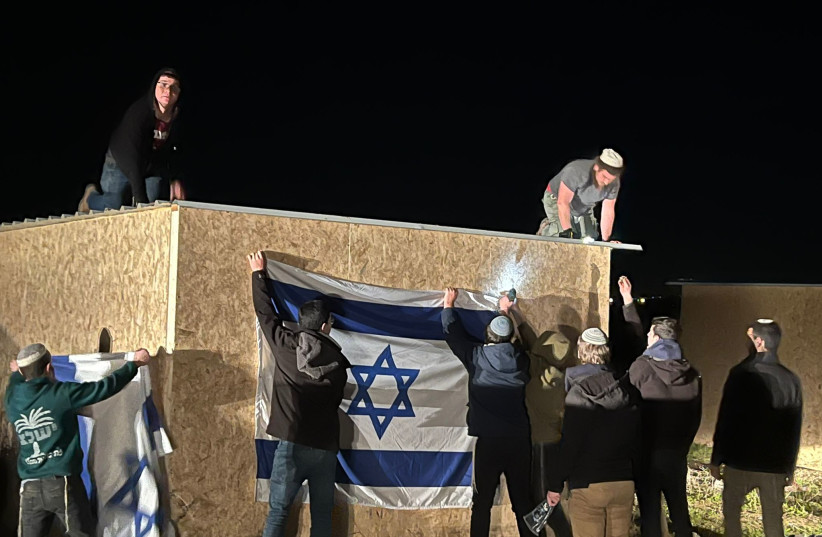  Right-wing activists hang an Israeli flag on a building they built in a new settlement named Ma'ale Paula. (photo credit: EZRI TOBY)