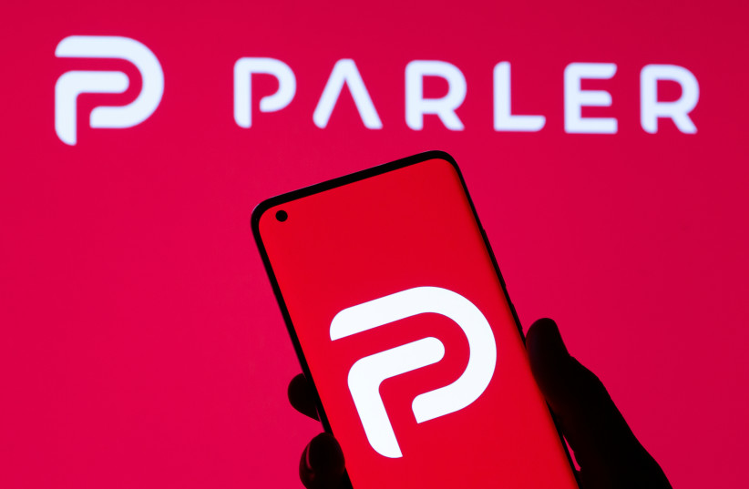 Woman holding smartphone with Parler logo in front of displayed same logo in this illustration taken May 17, 2021. (credit: REUTERS/DADO RUVIC)