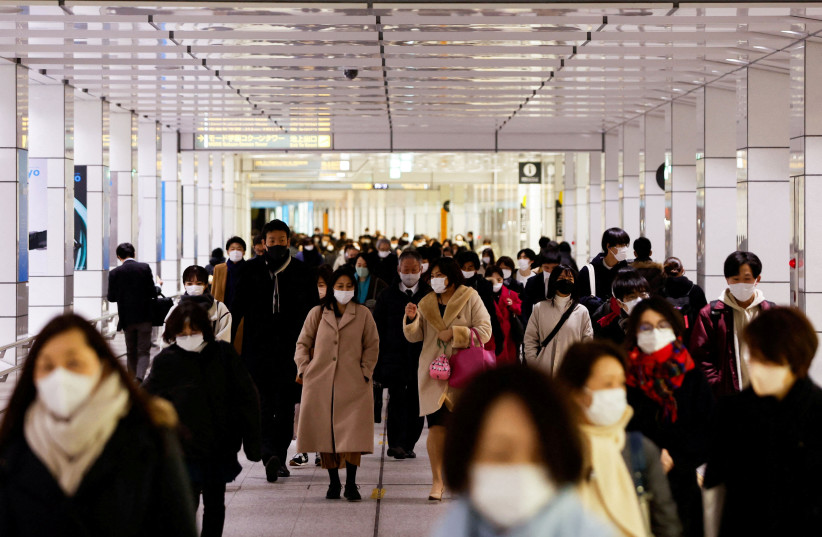  Passersby wearing protective face masks walk at a train station concourse, amid the coronavirus disease (COVID-19) pandemic, in Tokyo, Japan, February 9, 2022.  (credit: REUTERS/ISSEI KATO)