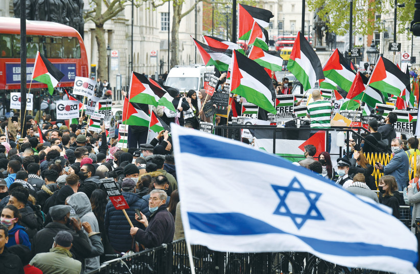  PRO-ISRAEL ACTIVISTS wave an Israeli flag as pro-Palestinian activists take part in a demonstration against Israel in central London last May. (photo credit: Justin Tallis/AFP via Getty Images)