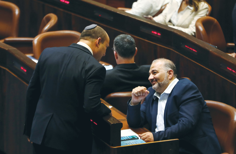  PRIME MINISTER Naftali Bennett chats with Ra’am leader Mansour Abbas in the Knesset in June. (photo credit: RONEN ZVULUN/REUTERS)