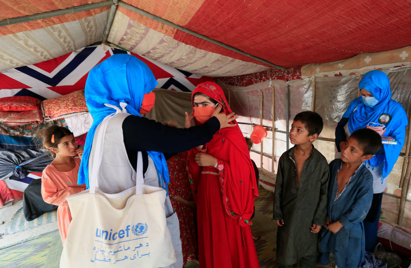  A UNICEF worker helps an internally displaced girl put on a face mask at a makeshift camp, amid the coronavirus disease (COVID-19) outbreak, in Jalalabad, Afghanistan June 22, 2020. (credit: REUTERS/PARWIZ)