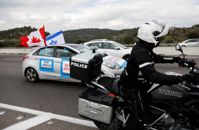  A car, which is part of an Israeli "Freedom Convoy", displays an Israeli flag adorned with red maple leaves as it heads to Jerusalem to protest against restrictions to contain the spread of the coronavirus disease (COVID-19), in Shoresh near Jerusalem, February 14, 2022. (photo credit: AMIR COHEN/REUTERS)