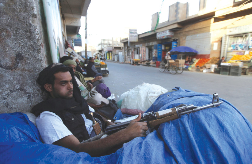  A HOUTHI fighter sits behind sandbags near a checkpoint in Sanaa, Yemen. (photo credit: MOHAMED AL-SAYAGHI/REUTERS)