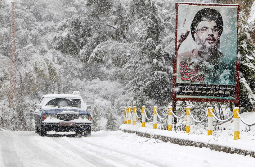  A snow covered taxi drives past a picture of Lebanon's Hezbollah leader Sayyed Hasan Nasrallah in Jbaa village, south Lebanon February 20, 2015. (credit: REUTERS/ALI HASHISHO)