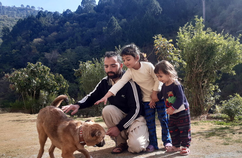  SAFE IN Islamabad: A father and his daughters pet a rescued pooch. (credit: Operation Magic Carpet)