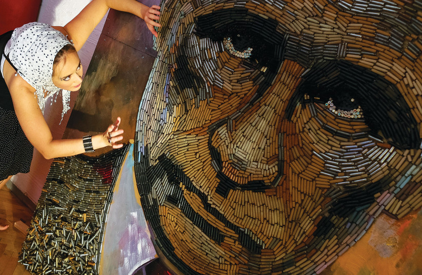  UKRAINIAN ARTIST Dariya Marchenko in 2015 works on a portrait of Russian President Vladimir Putin titles 'The Face of War', made out of 5,000 cartridges brought from the frontline in Eastern Ukraine. (photo credit: GLEB GARANICH/REUTERS)