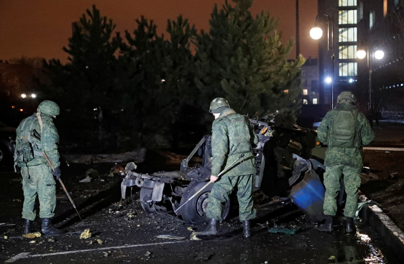 Specialists inspect a wreckage of a car that, according to the local authorities, was blown up near the government building, in the rebel-controlled city of Donetsk, Ukraine, February 18, 2022. (credit: REUTERS/ALEXANDER ERMOCHENKO)