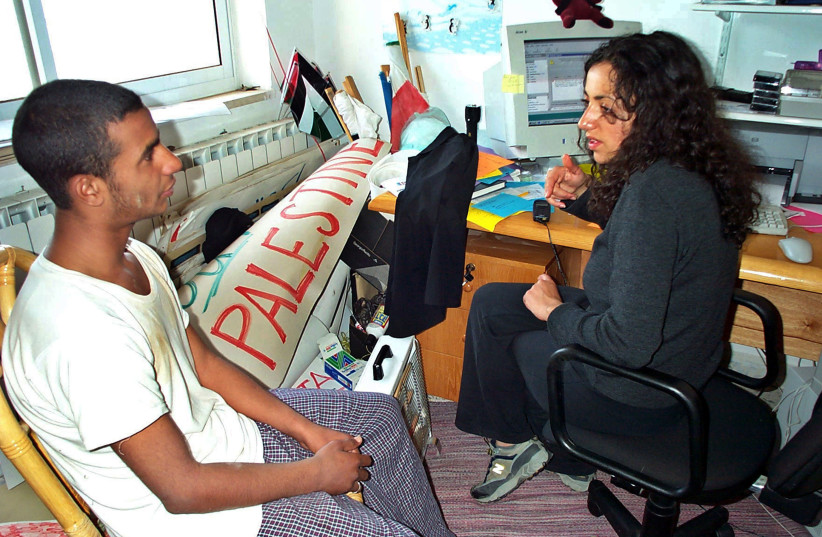  Huwaida Arraf sits with Abedallah Salih in the West Bank town of Ramallah, April 10, 2002. (credit: GETTY IMAGES/JTA)