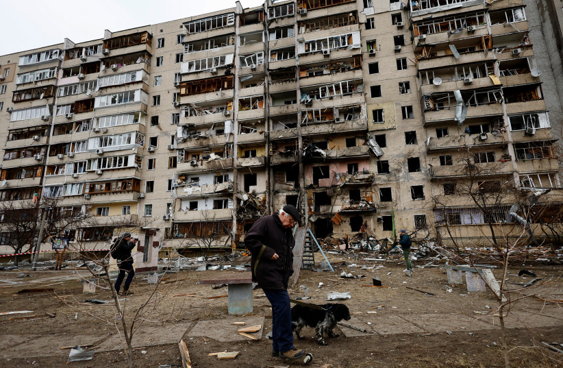  A person walks his dog in front of a damaged residential building, after Russia launched a massive military operation against Ukraine, in Kyiv, Ukraine February 25, 2022. (photo credit: UMIT BEKTAS/REUTERS)