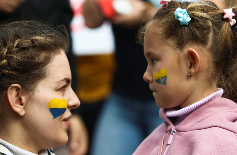  A mother talks to her child during a protest against Russia's military operation in Ukraine, outside the Presidential Palace in Nicosia, Cyprus February 26, 2022. (photo credit: REUTERS/YIANNIS KOURTOGLOU)