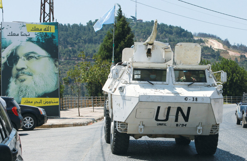  A UN PEACEKEEPERS (UNIFIL) vehicle drives past a poster depicting Hezbollah leader Hassan Nasrallah, near the Lebanese-Israeli border.  (photo credit: AZIZ TAHER/REUTERS)