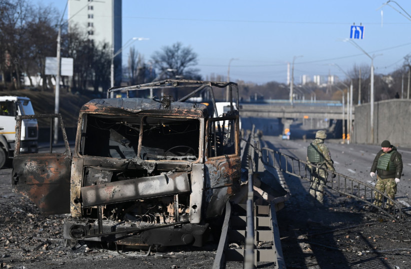  Ukrainian soldiers stand past a burnt Ukrainian army vehicle on the west side of the Ukrainian capital of Kyiv on February 26, 2022.  (credit: DANIEL LEAL/AFP via Getty Images)