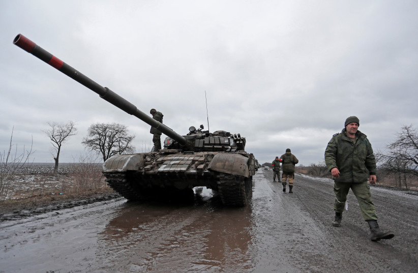  Servicemen of pro-Russian militia walk next to a military convoy of armed forces of the separatist self-proclaimed Luhansk People's Republic (LNR) on a road in the Luhansk region, Ukraine February 27, 2022. (photo credit: REUTERS/ALEXANDER ERMOCHENKO)