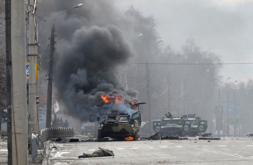  This photograph taken on February 27, 2022 shows a Russian Armoured personnel carrier (APC) burning next to unidentified soldier's body during fight with the Ukrainian armed forces in Kharkiv. (credit: SERGEY BOBOK/AFP via Getty Images)