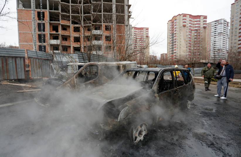  People are seen near cars, which locals said were burned during recent shelling, in the separatist-controlled city of Donetsk, Ukraine February 28, 2022.  (photo credit: REUTERS/ALEXANDER ERMOCHENKO)
