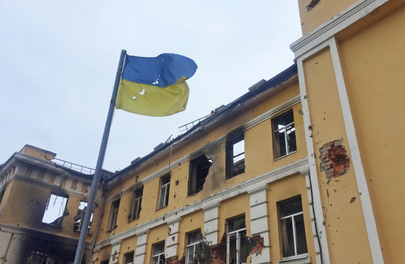  The Ukrainian national flag is seen in front of a school which, according to local residents, was on fire after shelling, as Russia's invasion of Ukraine continues, in Kharkiv, Ukraine February 28, 2022. (photo credit: Vitaliy Gnidyi/Reuters)