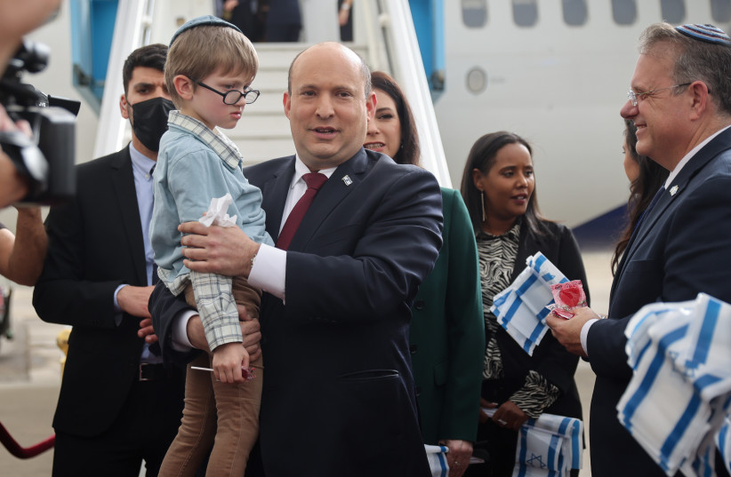 Prime Minister Naftali Bennett seen with Jewish immigrants fleeing the war in Ukraine on a rescue flight sponsored by the IFCJ, at Ben Gurion Airport near Tel Aviv on March 6, 2022. (credit: HADAS PARUSH/POOL)
