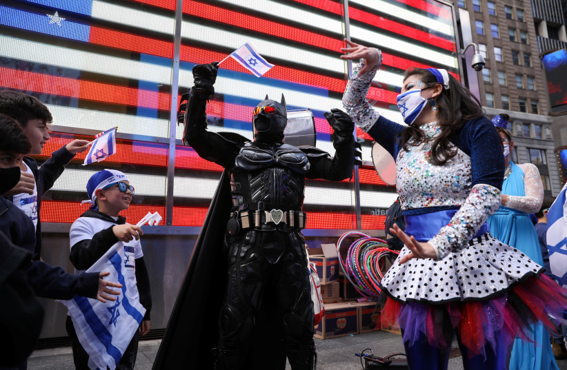 A man dressed as Batman waves a flag and joins children and women dancing to celebrate Israel's Independence Day, which marks the 73rd anniversary of the creation of the state, in Times Square in New York City, US, April 18, 2021 (credit: CAITLIN OCHS/REUTERS)