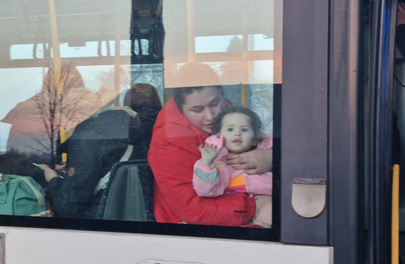 A mother and child seen through the window of a bus leaving the Siret border crossing between Ukraine and Romania and heading to the Romanian city of Suceava on March 15, 2022. (photo credit: MAYA MARGIT/THE MEDIA LINE)