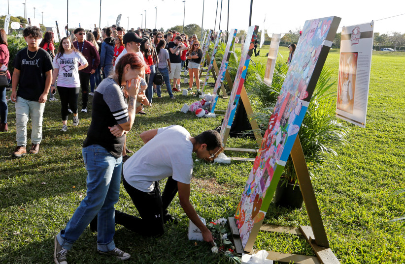 Flowers are placed at a memorial and photo of a victim before a memorial service on the one-year anniversary of the shooting which claimed 17 lives at Marjory Stoneman Douglas High School in Parkland, Florida, US, February 14, 2019. (photo credit: REUTERS/JOE SKIPPER)