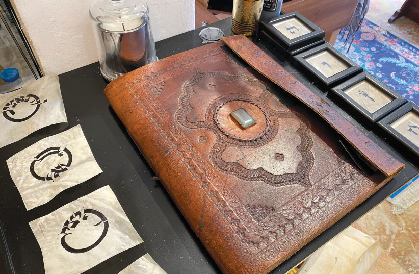  SURROUNDED BY calligraphed words and letters, this leather folder holds pieces from Kalman’s private collection. (credit: JORDANA BENAMI)