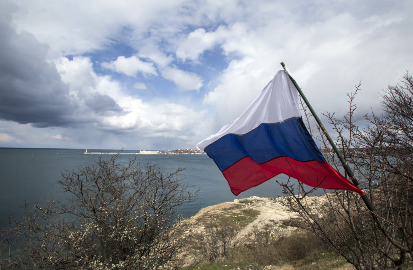  A Russian flag flies on the bank of the Black Sea during celebrations for the first anniversary of the Crimean treaty signing in Sevastopol, March 18, 2015. (credit: MAXIM SHEMETOV/REUTERS)