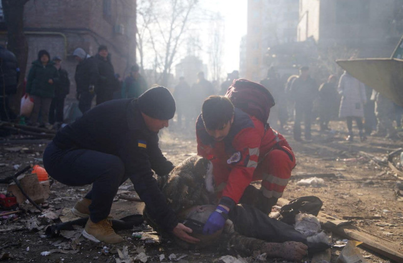  Rescuers help an injured person next to residential buildings damaged by shelling, as Russia's attack on Ukraine continues, in Kyiv, Ukraine, in this handout picture released March 18, 2022.  (credit: Press service of the State Emergency Service of Ukraine/Handout via REUTERS)