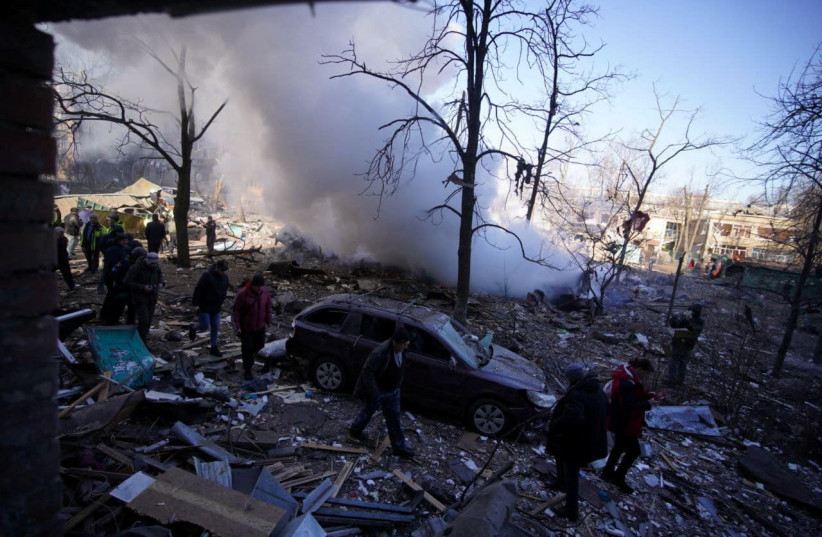  Locals walk next to residential buildings damaged by shelling, as Russia's attack on Ukraine continues, in Kyiv, Ukraine, in this handout picture released March 18, 2022. (credit: Press service of the State Emergency Service of Ukraine/Handout via REUTERS)