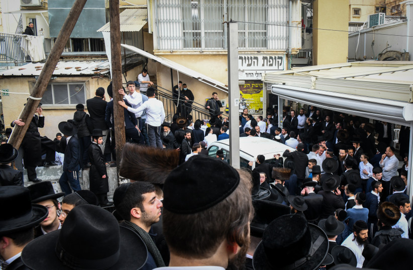 Des gens se rassemblent devant la maison du rabbin Chaim Kanievsky, décédé plus tôt dans la journée, dans la ville de Bnei Brak, le 18 mars 2022 (crédit photo : FLASH90)