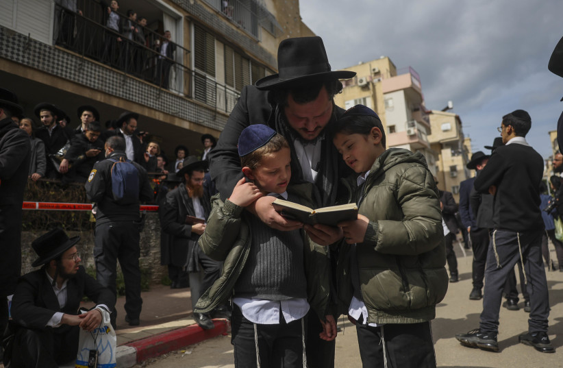 Ultra Orthodox Jewish men pray and wait as they gather outside the home of Rabbi Chaim Kanievsky who passed away, in the city of Bnei Brak, on March 20, 2022 (credit: YONATAN SINDEL/FLASH90)