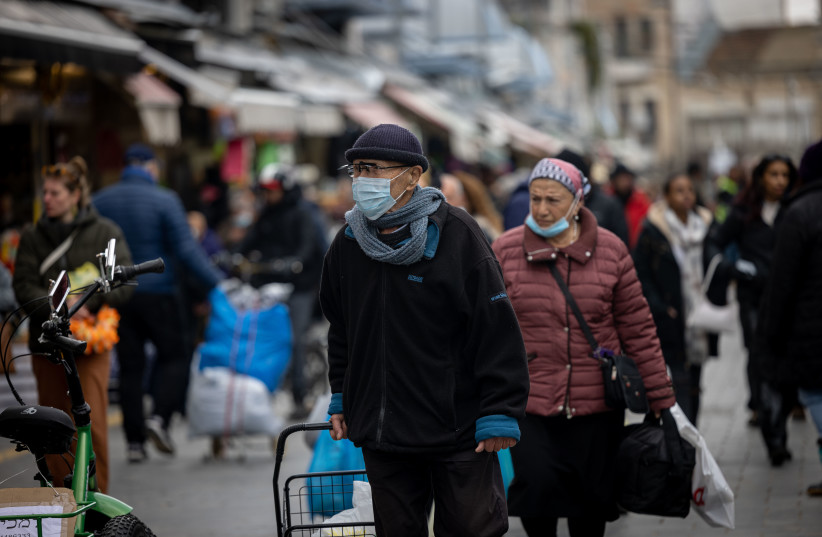  People some with face masks walk at the Machaneh Yehudah Market in Jerusalem, March 16, 2022. (photo credit: YONATAN SINDEL/FLASH90)