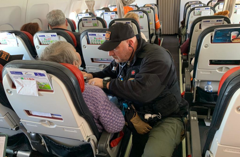  Dr. Zev Neuwirth checking a Ukrainian refugee who suffers from a medical condition while on board a rescue flight as part of Operation Orange Wings (credit: UNITED HATZALAH‏)
