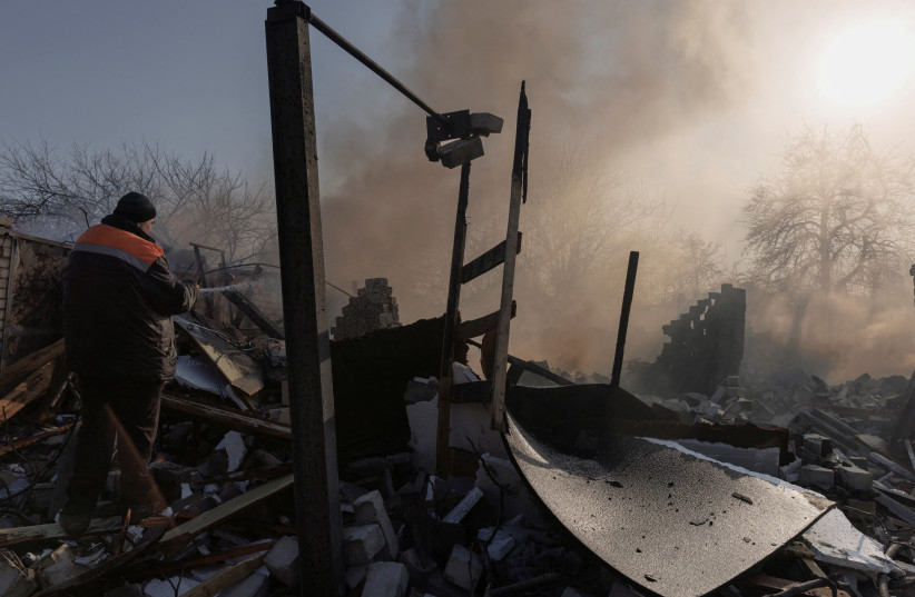 A resident extinguishes a fire after a bombing destroyed a family home in a northern district of Kharkiv as Russia's attack on Ukraine continues, Ukraine, March 24, 2022. (photo credit: REUTERS/THOMAS PETER)