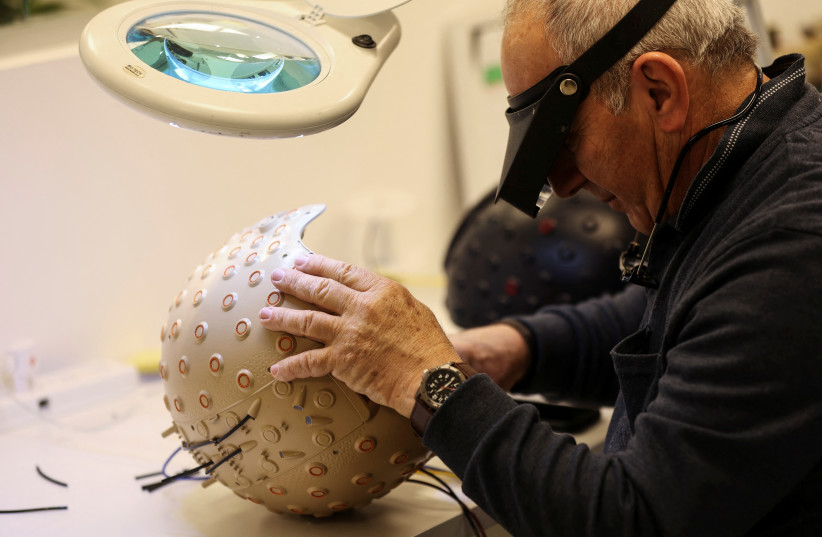  A worker at the Israeli startup Brain.Space builds an electroencephalogram (EEG) enabled helmet, due to be used in an experiment on the impact of a microgravity environment on the brain activity of astronauts, in Tel Aviv, Israel, March 23, 2022. (photo credit: REUTERS/NIR ELIAS)