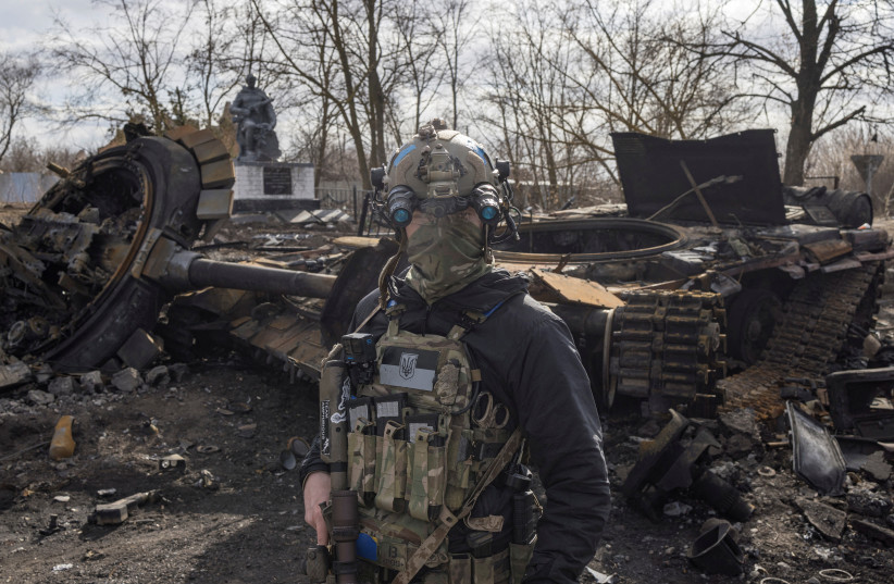  A Ukranian serviceman walks past the wreck of a Russian tank in the village of Lukyanivka outside Kyiv, as Russia's invasion of Ukraine continues, Ukraine, March 27, 2022 (photo credit: REUTERS/MARKO DJURICA)