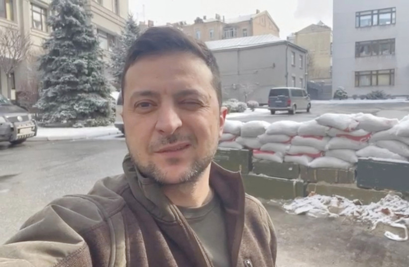  UKRAINIAN PRESIDENT Volodymyr Zelensky winks in a video statement with sand bags behind him in Kyiv, in this still image obtained from social media.  (photo credit: Instagram/Volodymyr Zelensky/via Reuters)