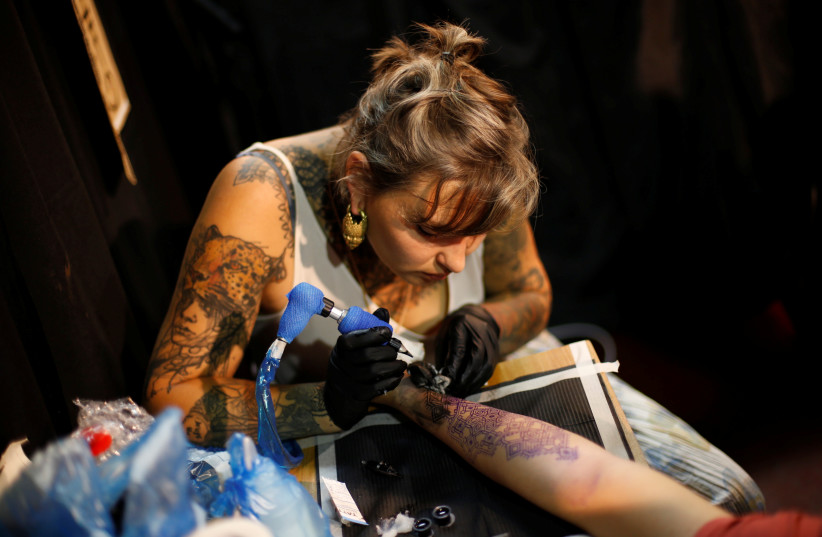  A tattoo artist at work during the annual Israel Tattoo Convention in Tel Aviv. (credit: BAZ RATNER/REUTERS)